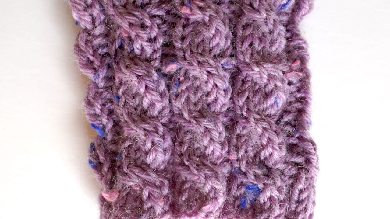 Close-up photo of basic cable stitch pattern in purple yarn