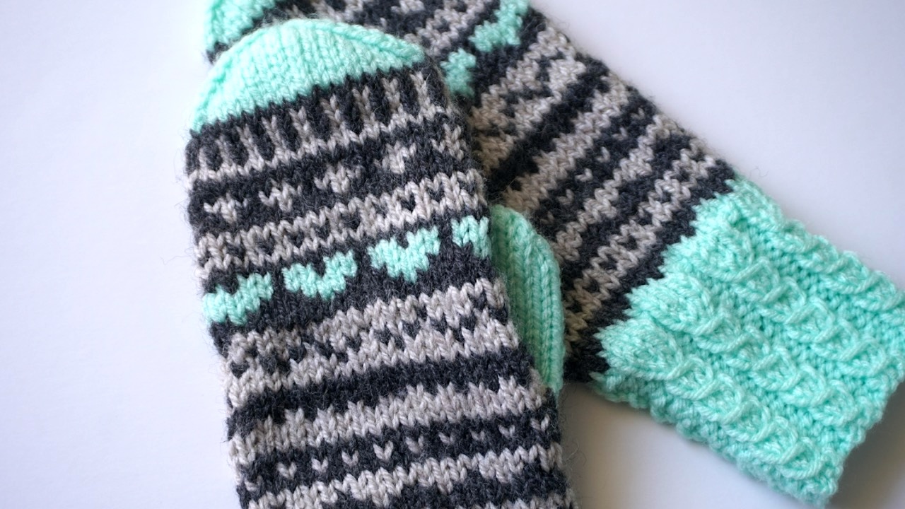 Knitted mittens featuring colorwork pattern in dark gray, light gray and pastel mint yarn