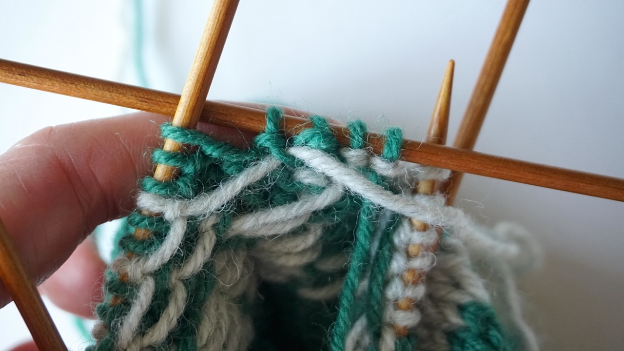 Close-up knitting photo of the wrong side of the colorwork pattern showing how to catch long floats