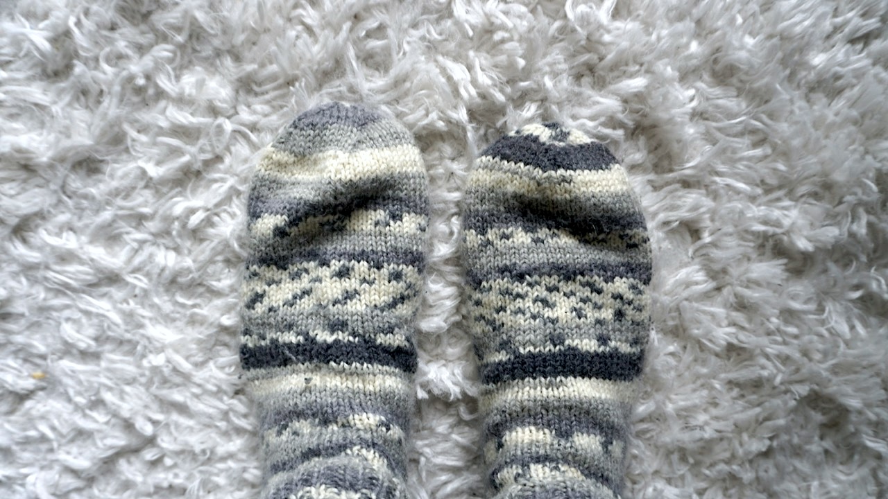 A pair of too loosely knitted socks on a white carpet