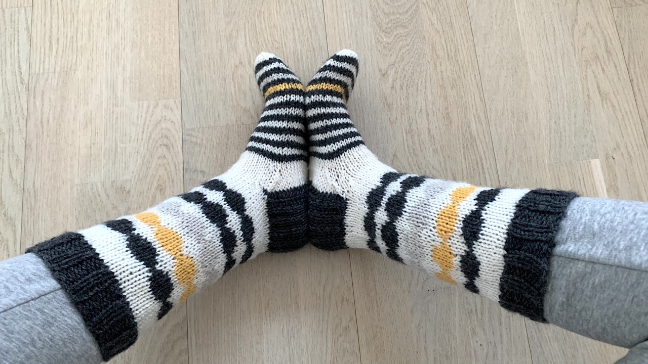 Feet wearing wool socks with black, white and yellow stripes and polka dots