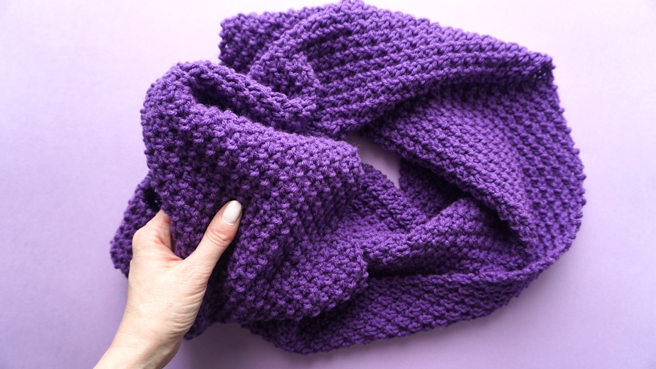 Knitted infinity scarf in moss stitch pattern in dark purple yarn