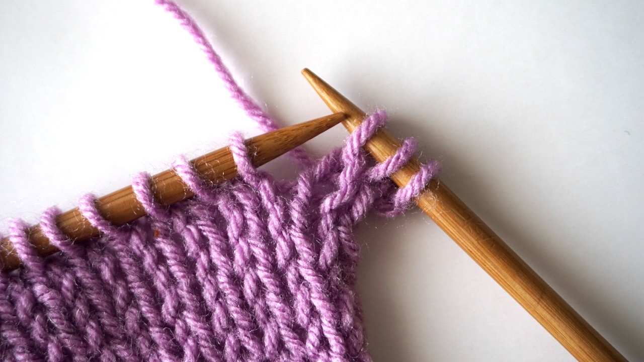 An unfinished knitting project with three stitches on the right-hand needle