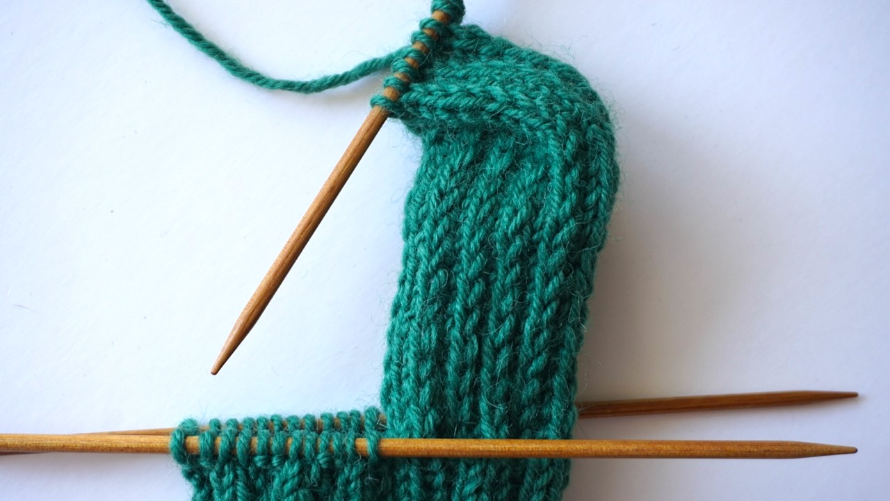 Step-by-step knitting photo showing the heel turn in dark green yarn