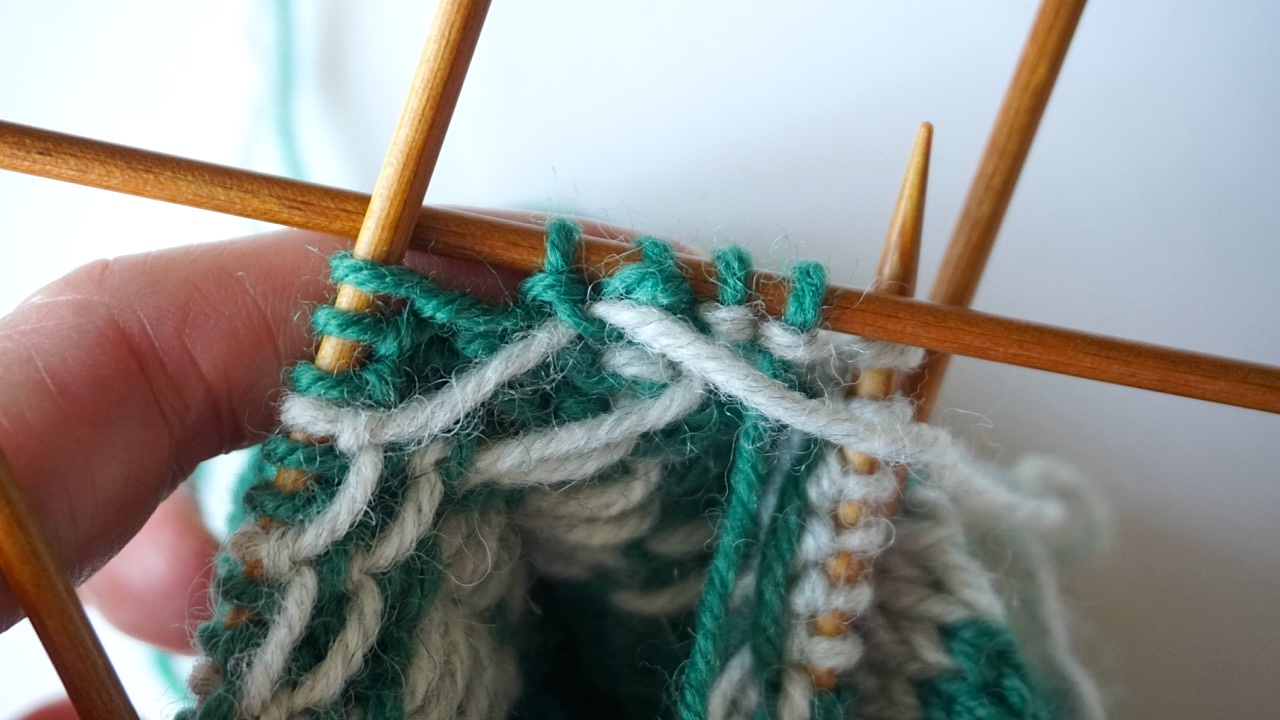 Step-by-step knitting photo showing the wrong side of the colorwork sock and how to catch long floats