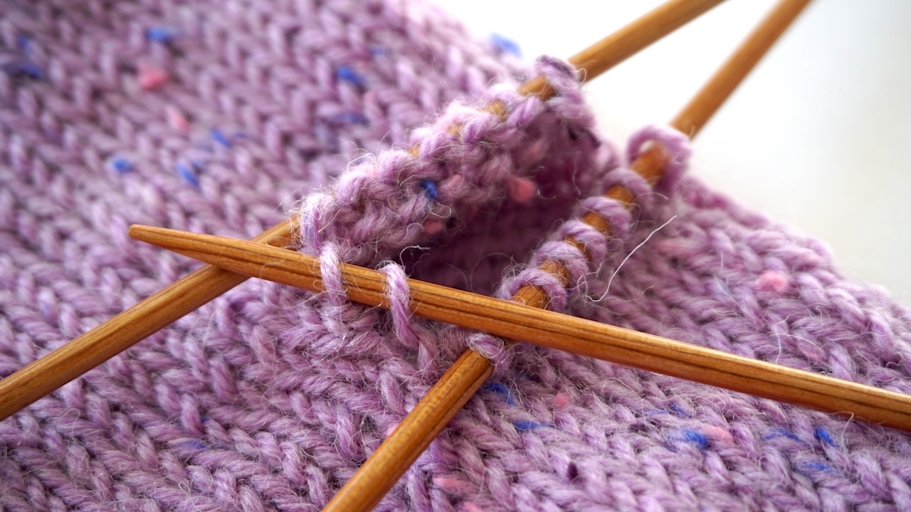 Step-by-step knitting photo showing how to pick up the thumb stitches when knitting mittens
