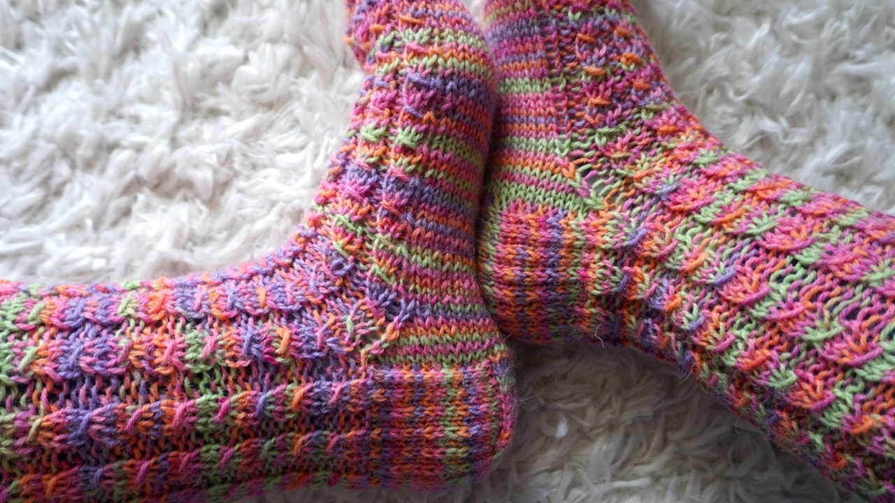 Feet wearing colorful knitted socks in mock cable stitch pattern