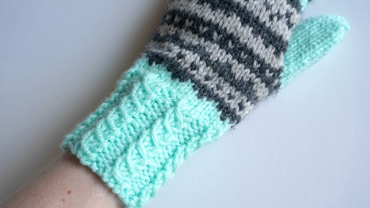 Knitted mitten featuring faux cable stitch in soft mint green yarn