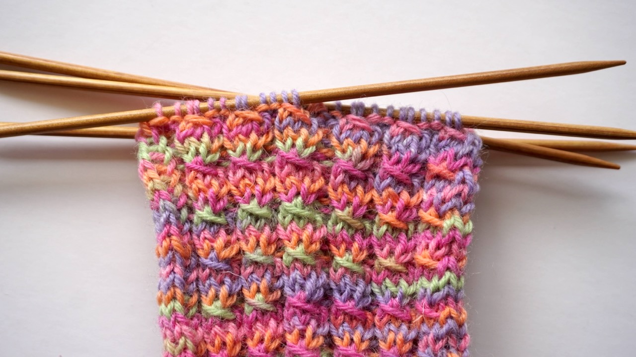 Close-up photo of mock cable knit stitch texture in colorful yarn showing twisted stitches