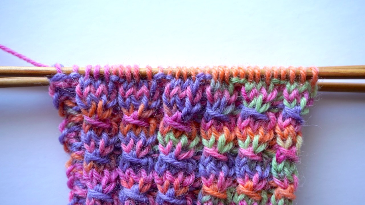 Close-up photo of a faux cable stitch in colorful yarn showing the cable-like texture