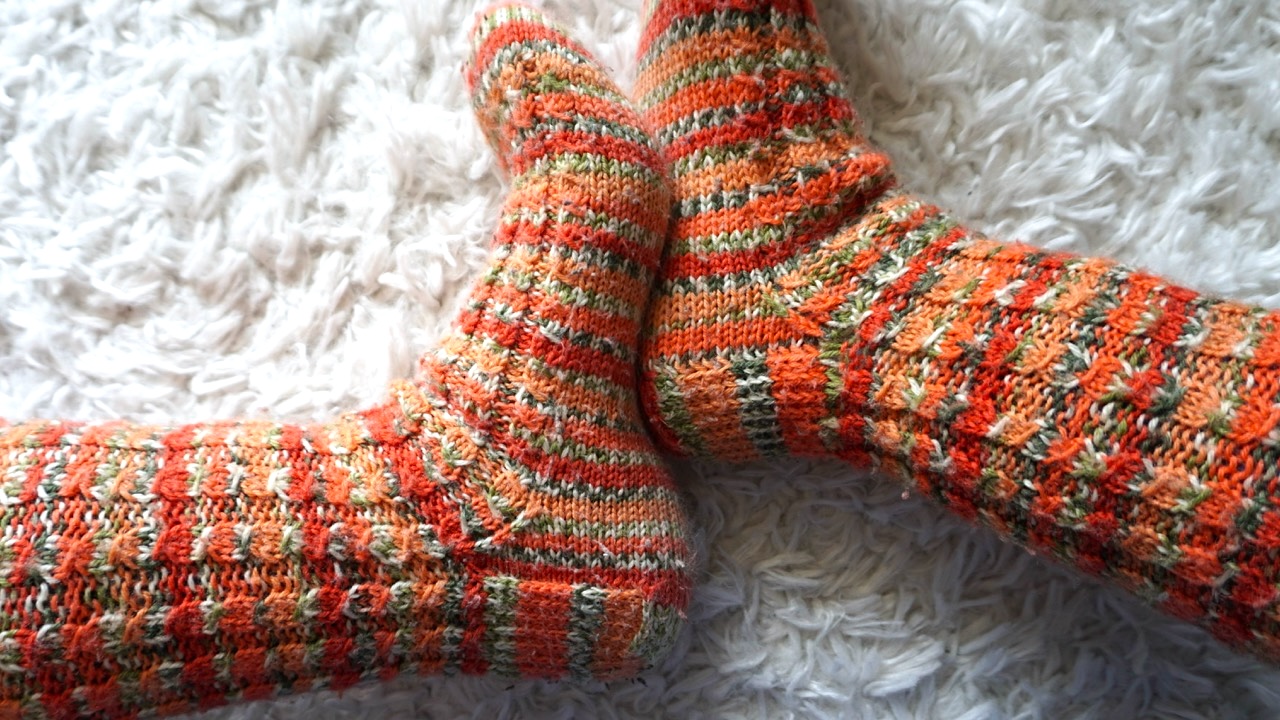 Feet wearing faux cable socks in vibrant fall colors