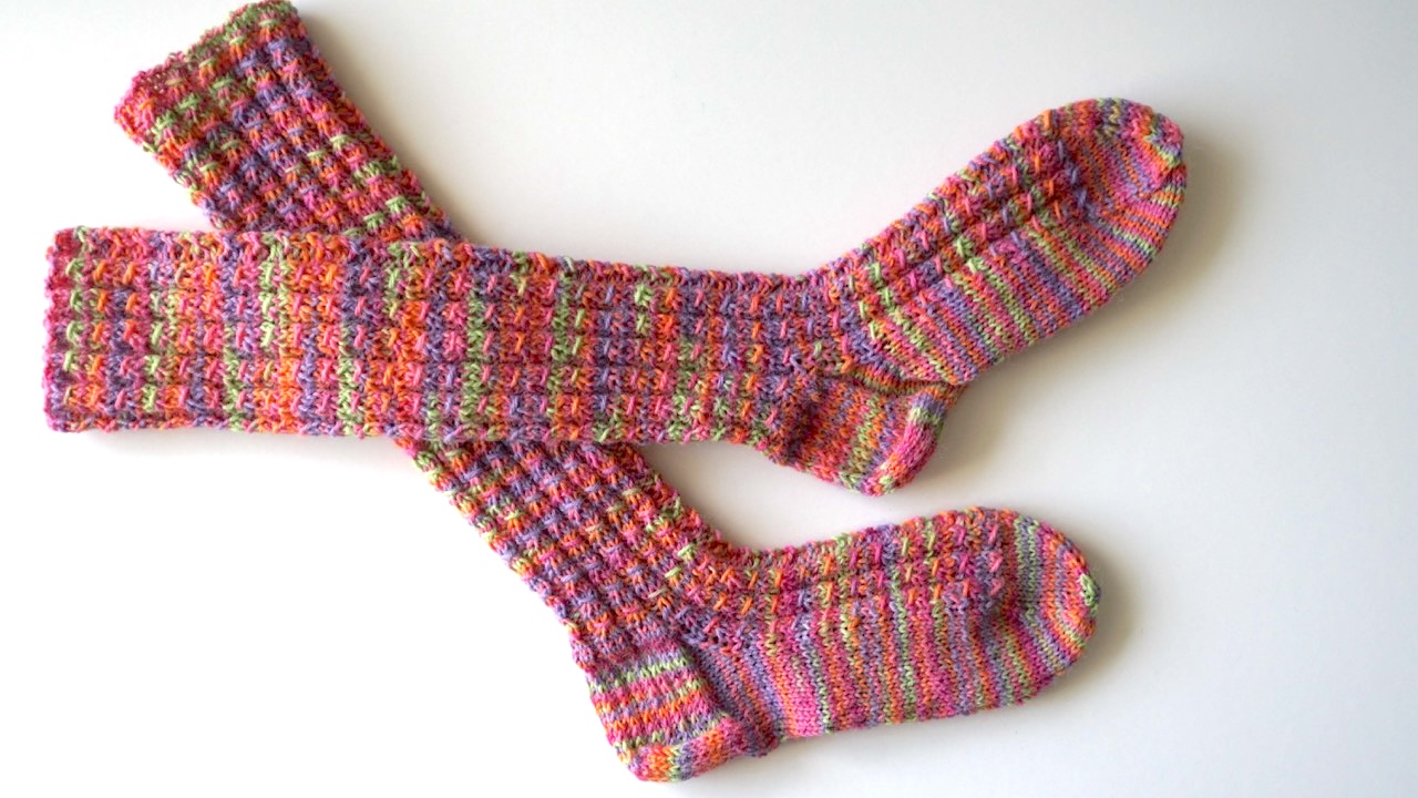 Knitted socks featuring mock cable stitch pattern in bright and colorful yarn