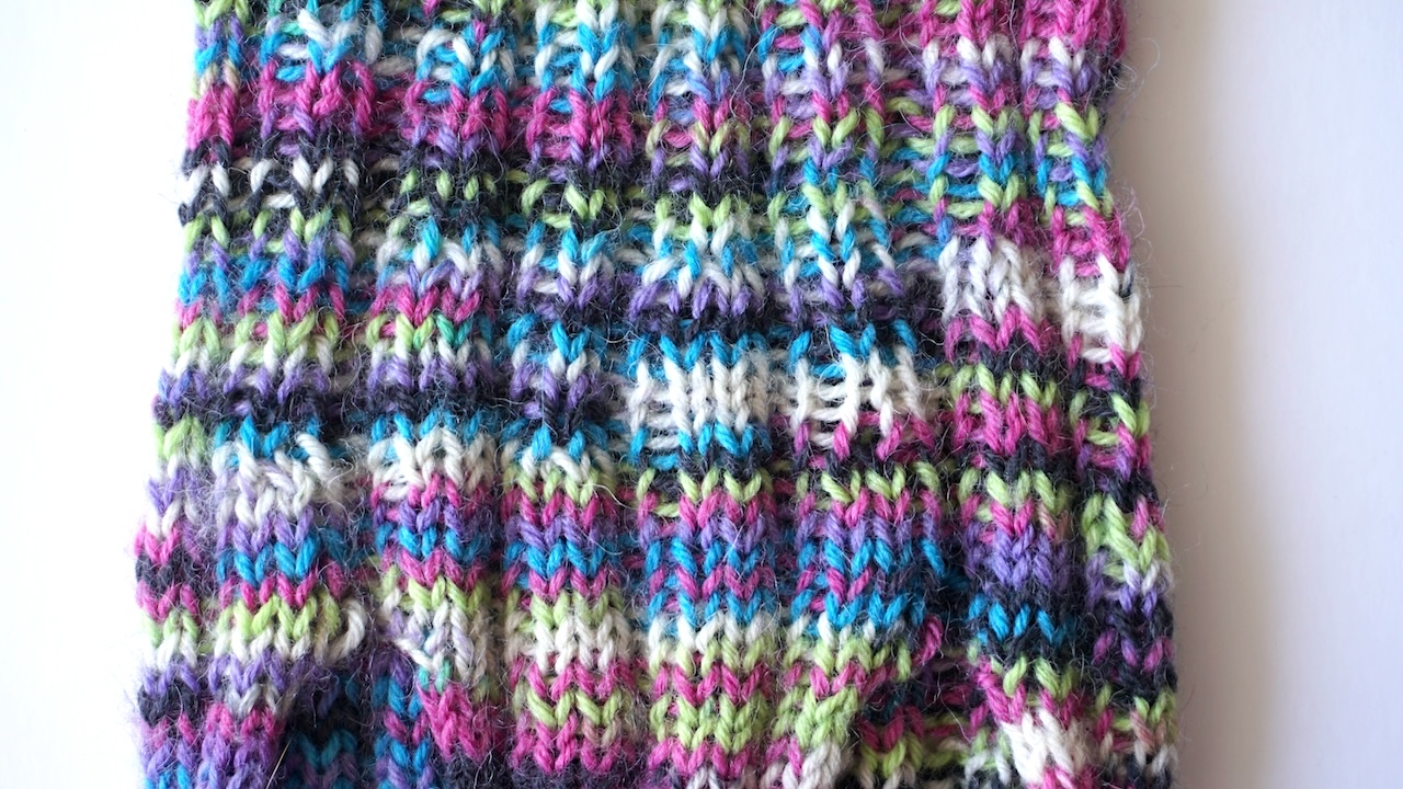 Close-up photo of ribbed upper body of a knitted dog sweater in multicolored yarn