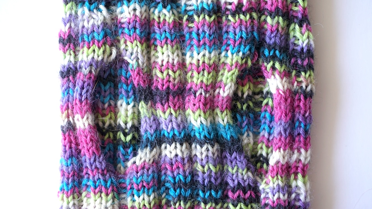Close-up photo of the leg openings of a knitted dog sweater pattern in multicolored yarn
