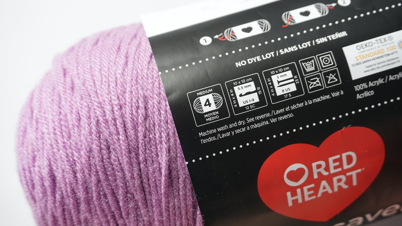 A purple skein of yarn with a label showing the yarn weight category symbol